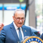 Chuck Schumer giving speech outdoors.