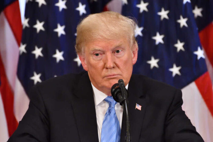 shutterstock_1191272251.jpg featured image Donald Trump speaking with American flags in background.