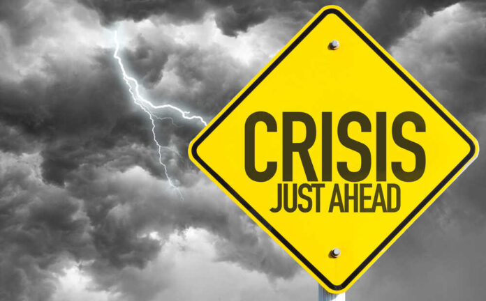 shutterstock_327481232.jpg featured image Yellow sign reading Crisis Just Ahead with stormy sky