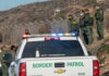 Border Patrol officers detaining individuals near a fence.