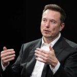 Elon Musk speaking and gesturing with hands in discussion.