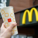 Hand holding McDonalds cup in front of sign