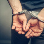 Person with handcuffs behind their back.