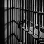Rusty prison cell bars in dim lighting.
