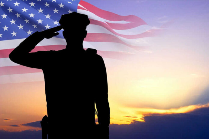shutterstock_2461746929.jpg Silhouette of soldier saluting in front of American flag