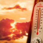 Thermometer displaying high temperature against a sunset background