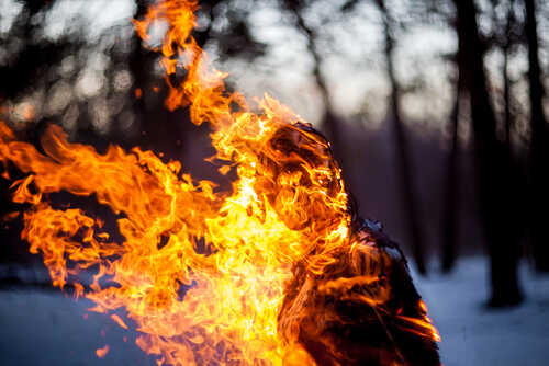 shutterstock_585407174.jpg A silhouette of a person engulfed in flames in a forest setting