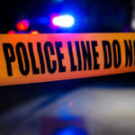 Police tape with flashing lights in the background