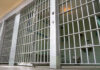Empty prison cell with metal bars and toilet