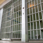 Empty prison cell with metal bars and toilet