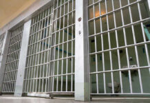 Empty prison cell with metal bars and toilet
