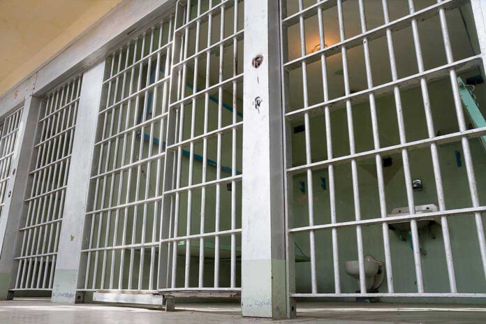 Empty prison cell with metal bars and toilet