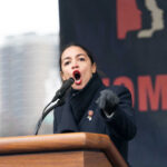 Alexandria Ocasio-Cortez speaking at a podium