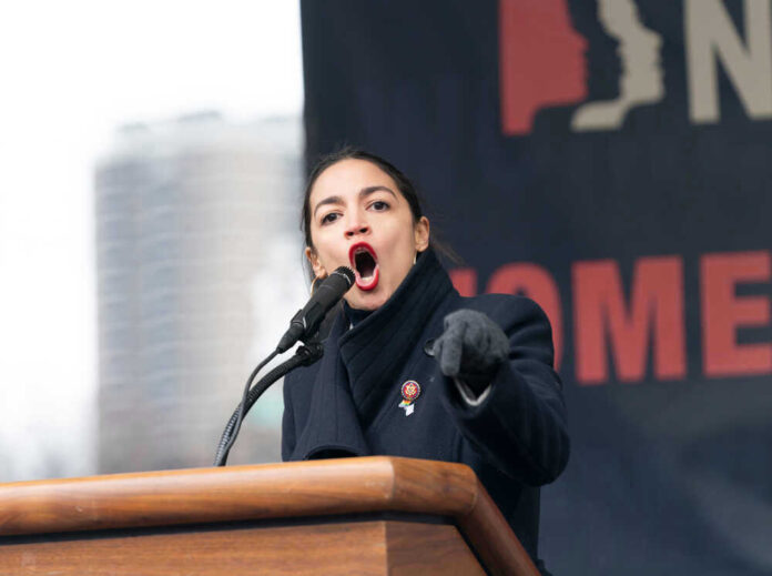 Alexandria Ocasio-Cortez speaking at a podium