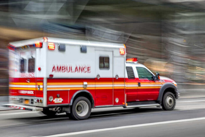 Red and white ambulance driving on a city street