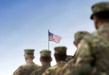 Soldiers in uniform with American flag in background