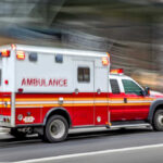 Red and white ambulance driving on a city street