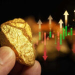 Hand holding gold nugget with financial market chart