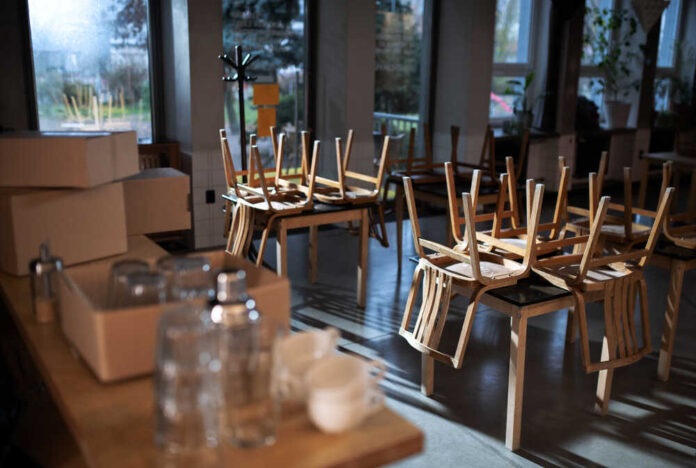 An empty cafe with stacked wooden chairs and boxes on a table