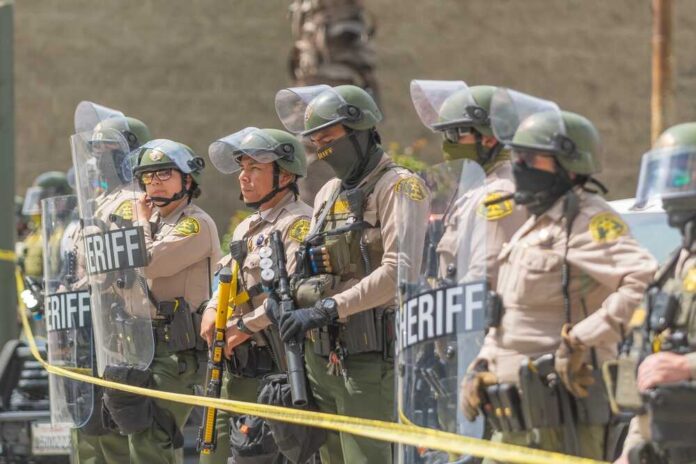Line of police officers in riot gear standing behind shields