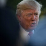 Donald Trump speaking outdoors, partially obscured