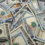 Scattered hundred dollar bills with Benjamin Franklins portrait.