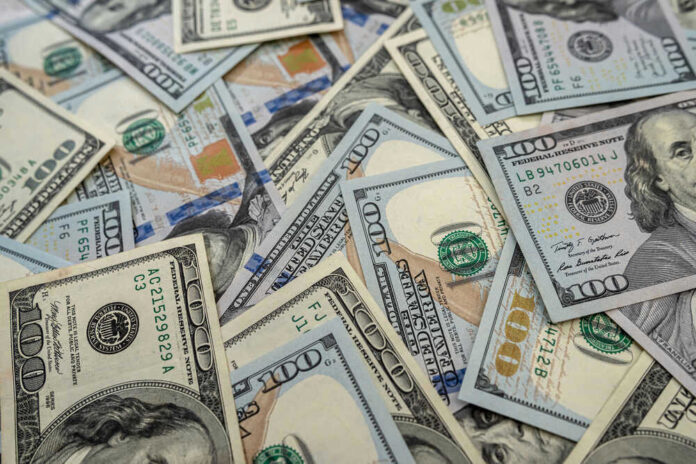 Scattered hundred dollar bills with Benjamin Franklins portrait.