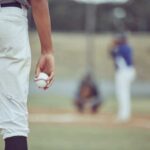 A young baseball player holding a baseball while preparing to pitch