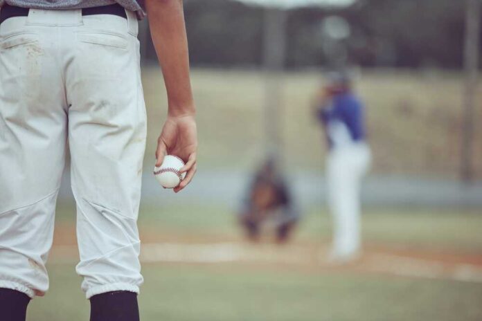 A young baseball player holding a baseball while preparing to pitch