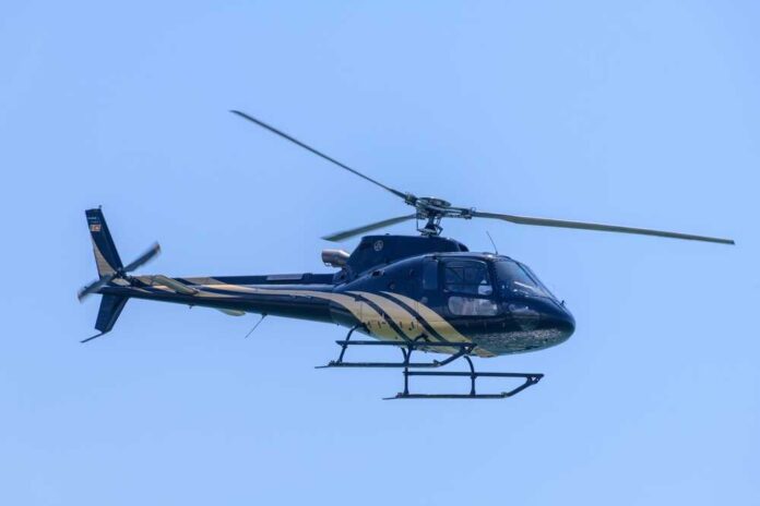 A helicopter flying against a clear blue sky