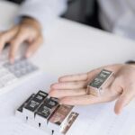 Person holding a silver bar while using a calculator in a business setting
