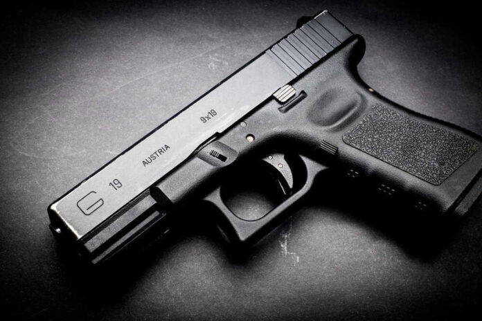 Black Glock 19 pistol on a dark surface.
