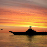 Trump’s Orders Military To Shift Toward Terrorist Regime Silhouette of an aircraft carrier at sunset