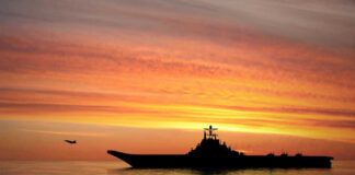 Silhouette of an aircraft carrier at sunset