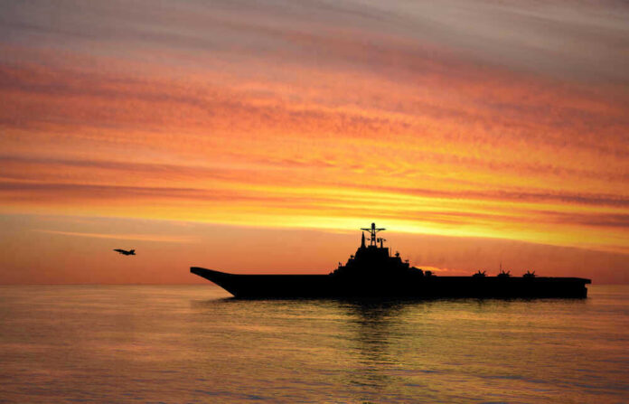 Silhouette of an aircraft carrier at sunset