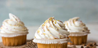Three decorated cupcakes with swirled frosting and colorful sprinkles