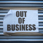 Retail Giant FALLS — Bankruptcy Sparks Fear Out of Business sign on closed store shutters.