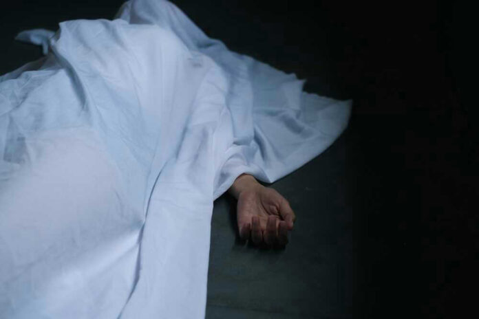 shutterstock_2194040069.jpg Hand emerging from under white sheet on dark surface.