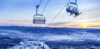 Ski lift overlooking a snowy mountain landscape at sunset