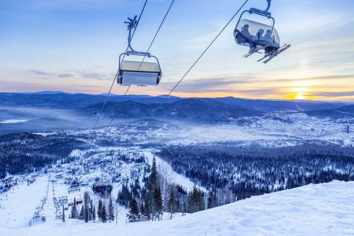 Ski lift overlooking a snowy mountain landscape at sunset
