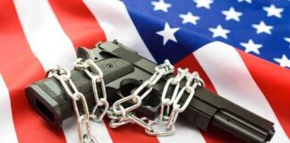 A handgun wrapped in chains on an American flag