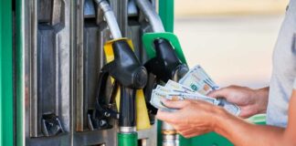 Person holding cash at a gas station while preparing to refuel