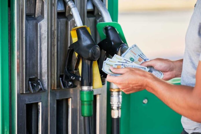 Person holding cash at a gas station while preparing to refuel