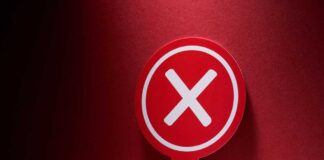 Red sign with a white cross symbol on a dark background