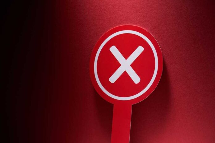 Red sign with a white cross symbol on a dark background