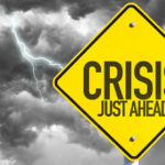 Yellow sign reading Crisis Just Ahead with stormy sky