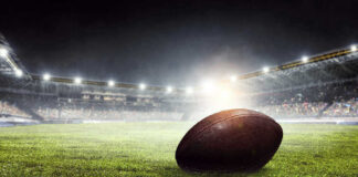 Football on field in illuminated stadium at night.