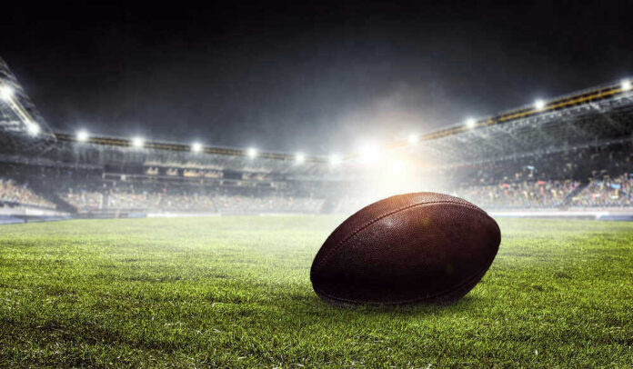 shutterstock_648227854.jpg Football on field in illuminated stadium at night.