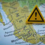 A close-up of a map of Mexico with a yellow warning sign placed on it