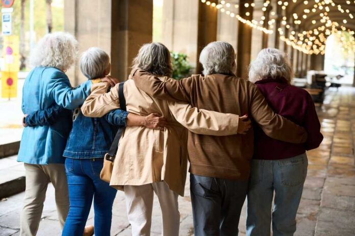 Group of elderly friends walking arm in arm outdoors